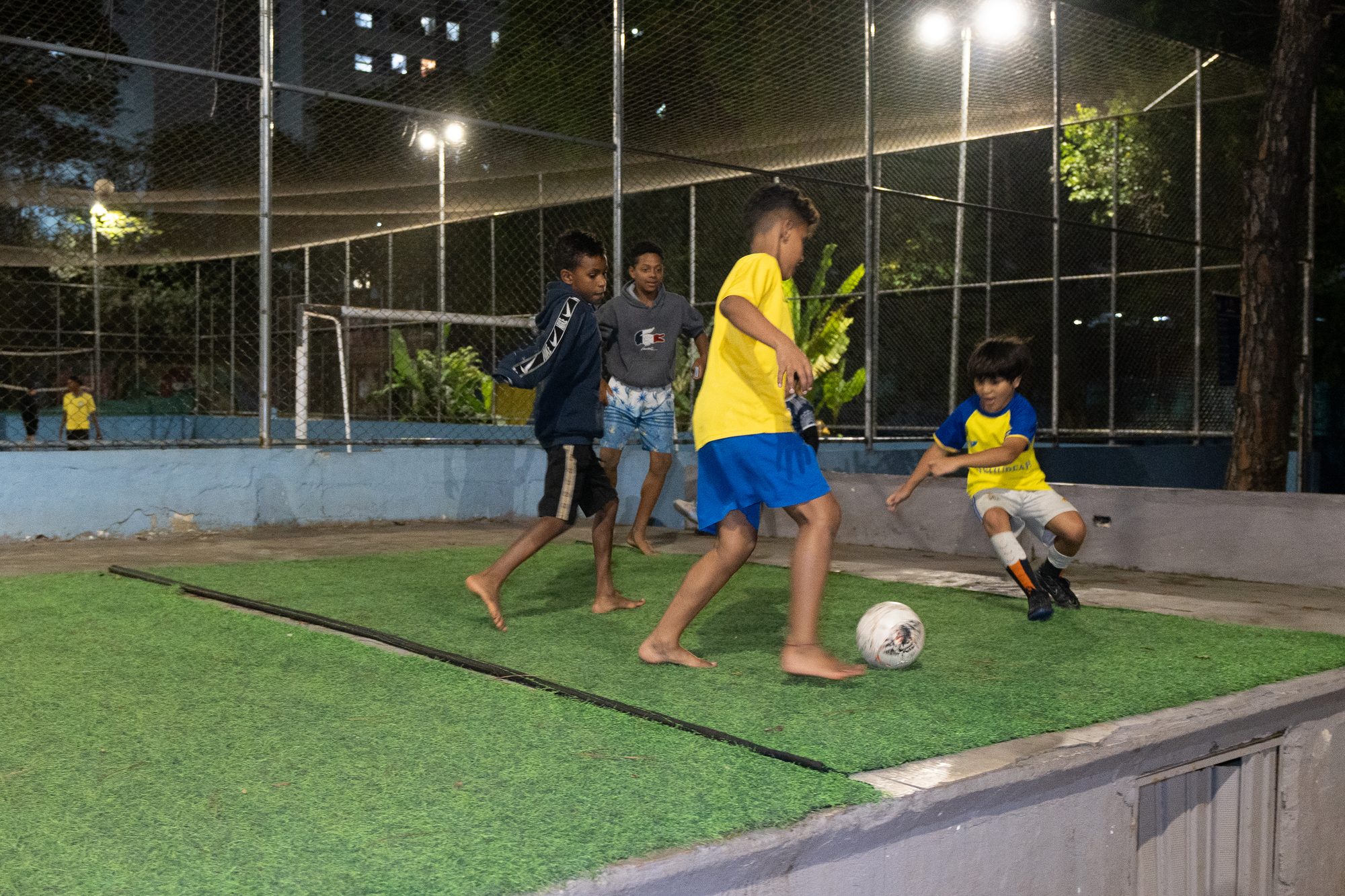 Crianças jogando bola no gramado do Complexo