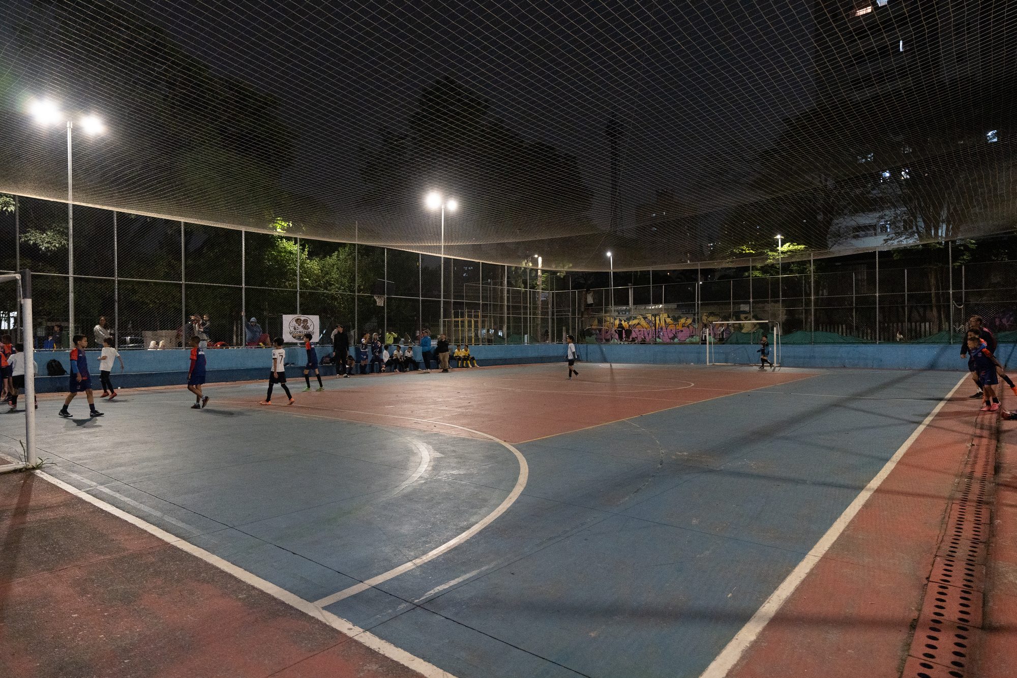 Quadra de futsal vazia à noite, com os refletores acesos