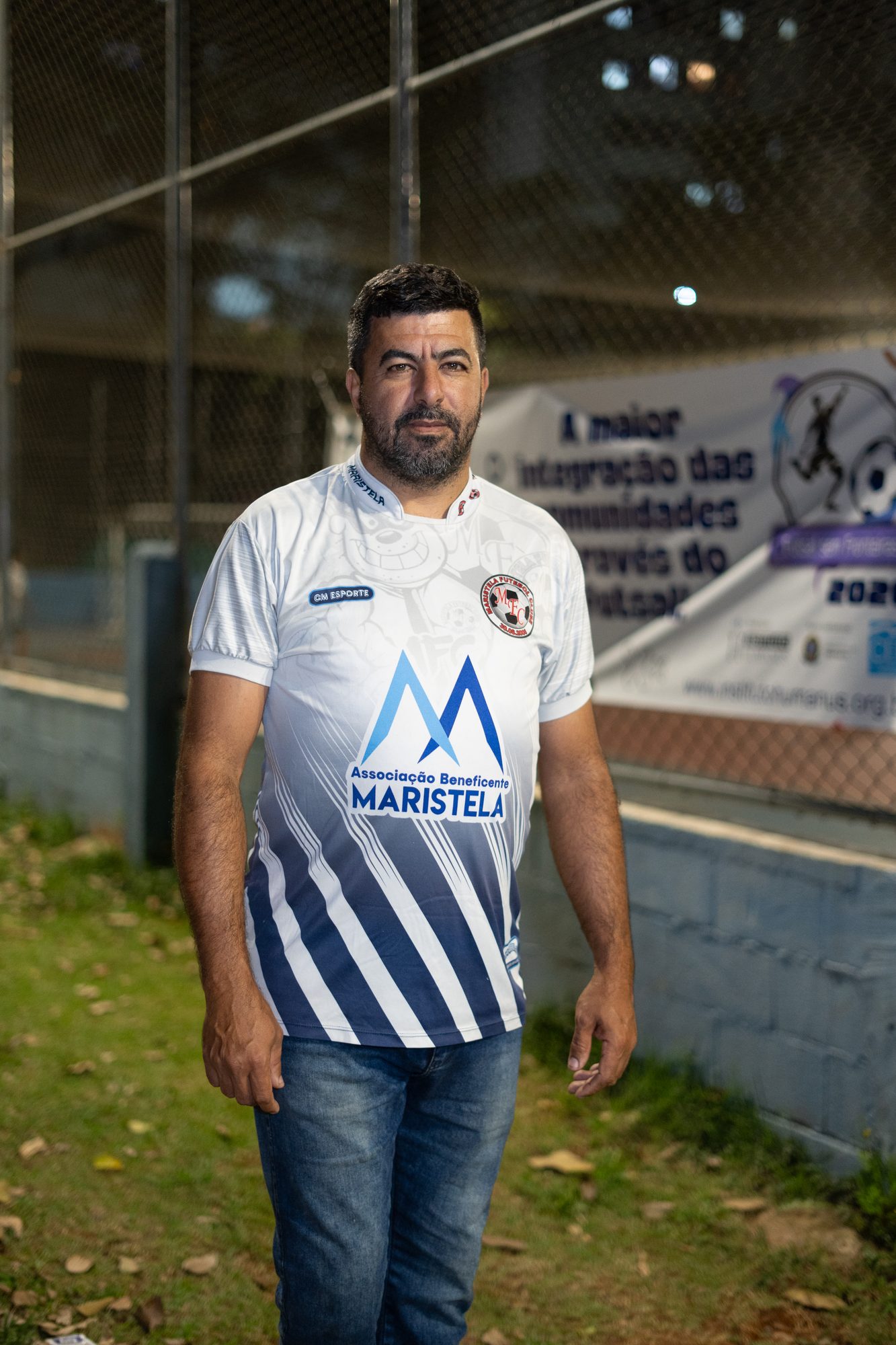 Homem com a camisa da Maristela ao lado da faixa do evento