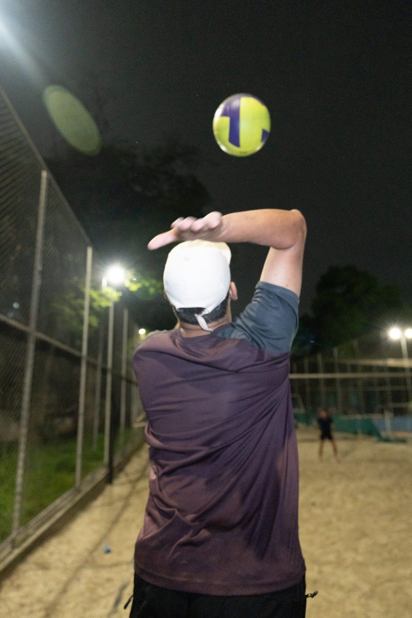 Saque de vôlei na quadra de areia, à noite