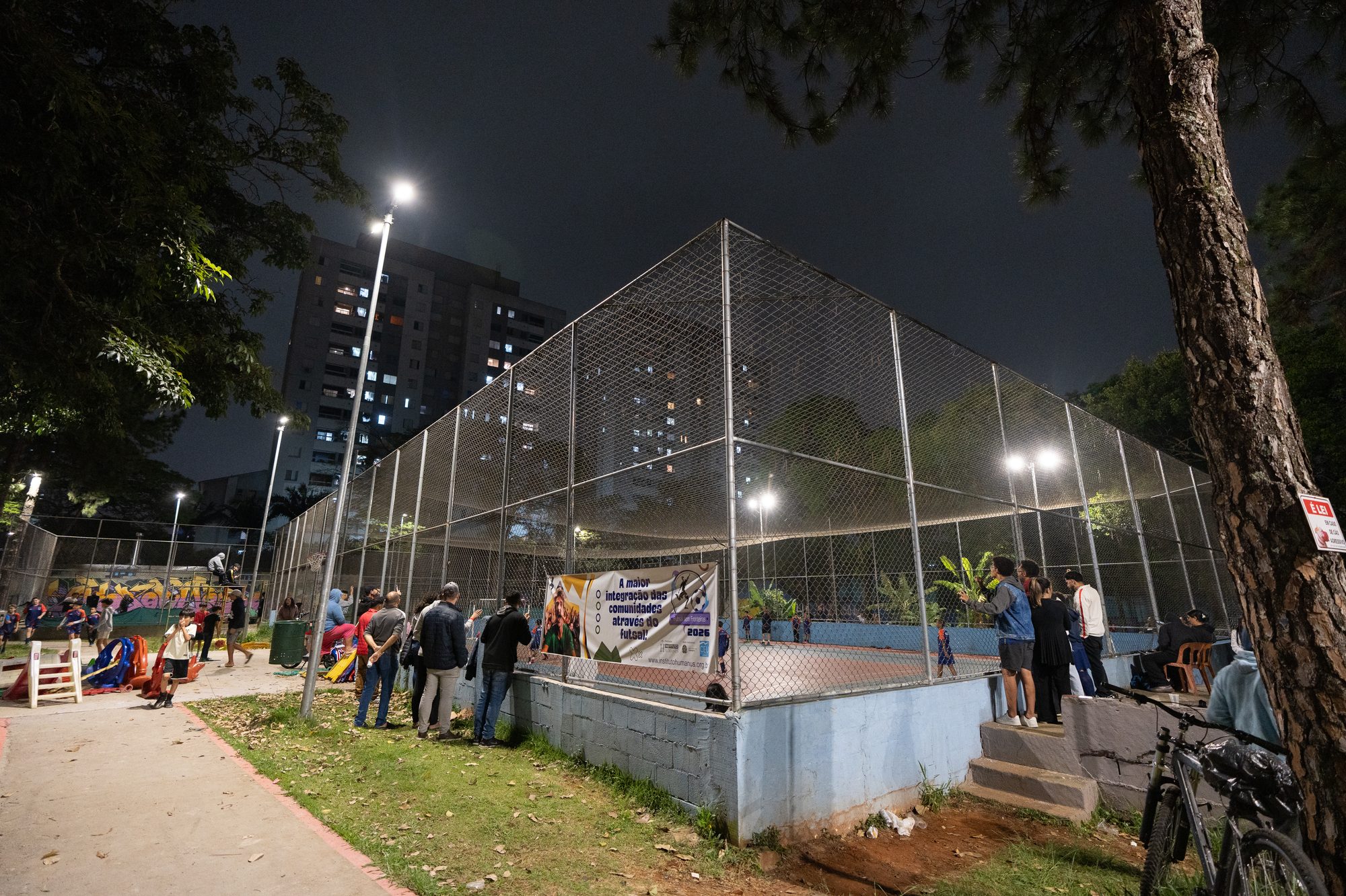 Quadra iluminada à noite, com a torcida ao redor